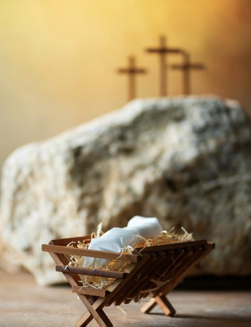 Christian Christmas, Easter concept. Born to Die, Born to Rise. Wooden manger, three crosses